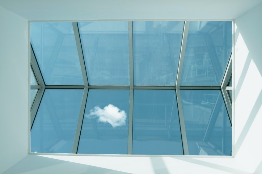 looking up at large skylight with fluffy white cloud and blue sky background